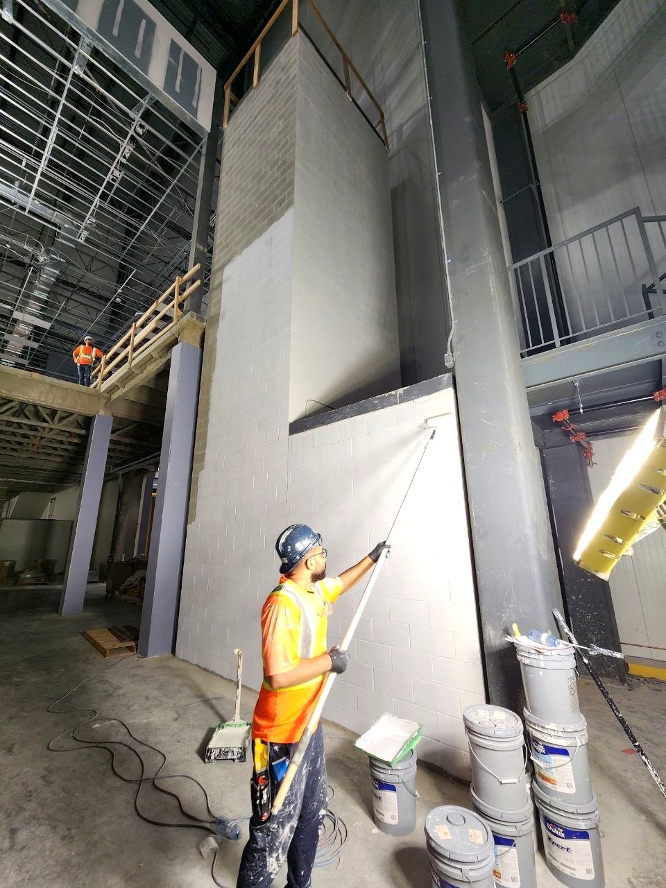 Pllosso worker painting a high industrial wall